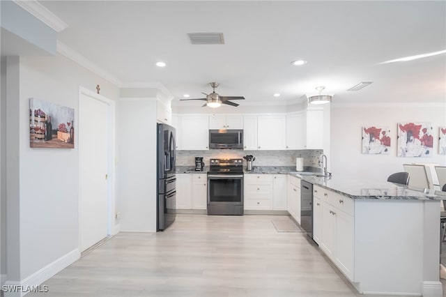 kitchen with backsplash, kitchen peninsula, light stone countertops, white cabinetry, and stainless steel appliances