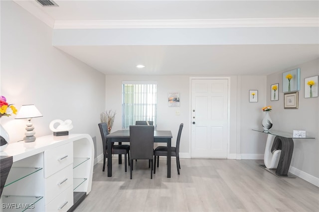 dining area with ornamental molding and light hardwood / wood-style flooring