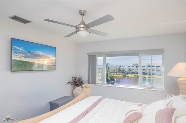 bedroom with ceiling fan and a water view