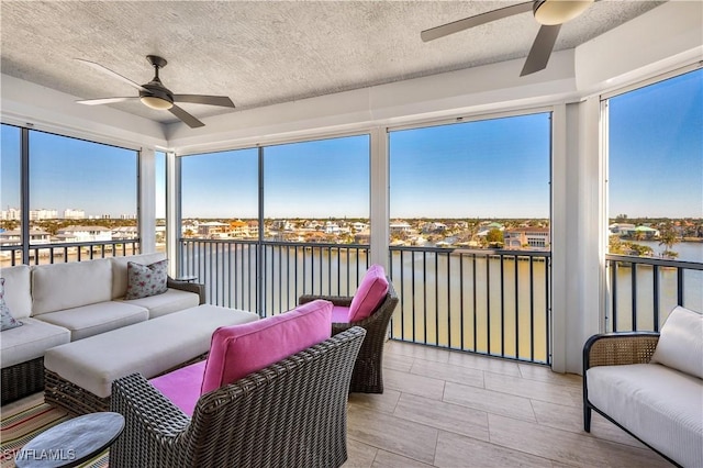 sunroom / solarium featuring ceiling fan and a water view