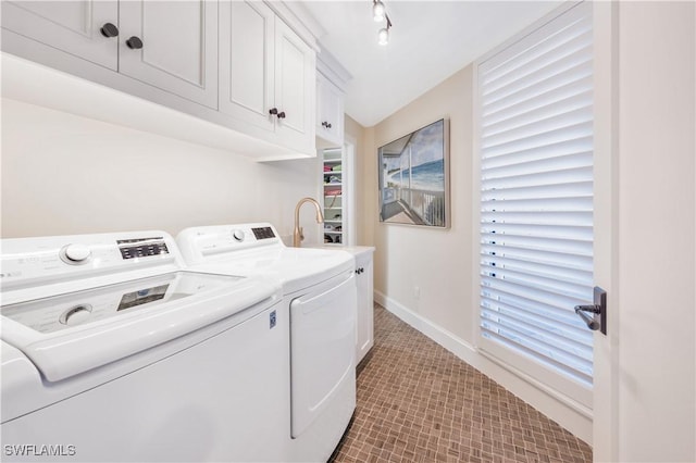 clothes washing area featuring separate washer and dryer and cabinets