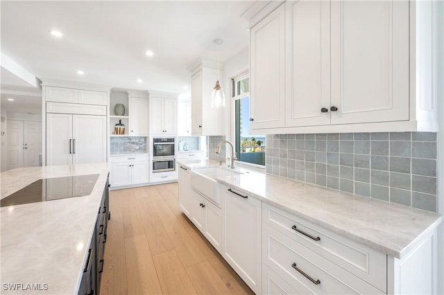 kitchen featuring pendant lighting, light stone counters, and white cabinetry