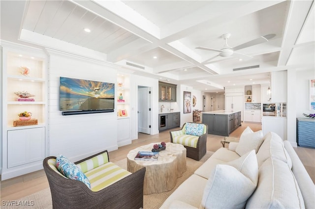 living room featuring coffered ceiling, ceiling fan, indoor wet bar, beam ceiling, and light hardwood / wood-style flooring