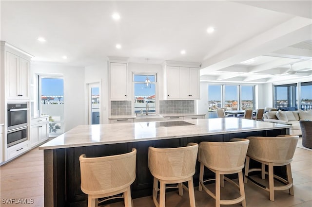 kitchen featuring decorative backsplash, beam ceiling, white cabinetry, and a large island