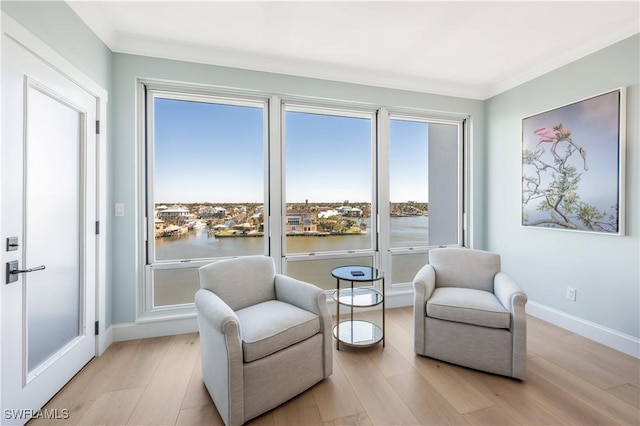 living area with a water view, crown molding, and light hardwood / wood-style floors