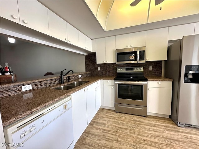 kitchen with dark stone counters, white cabinets, sink, light wood-type flooring, and stainless steel appliances