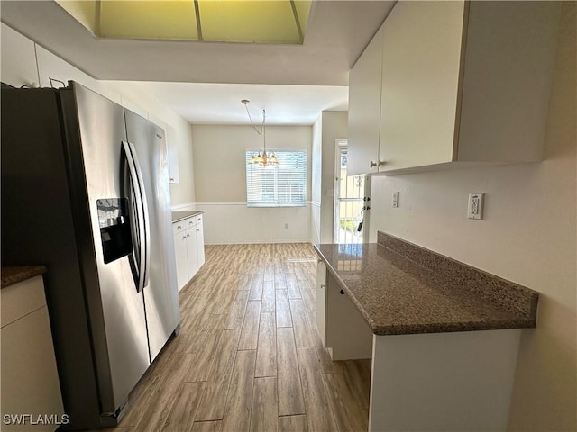 kitchen with white cabinetry, stainless steel refrigerator with ice dispenser, hardwood / wood-style floors, a chandelier, and pendant lighting