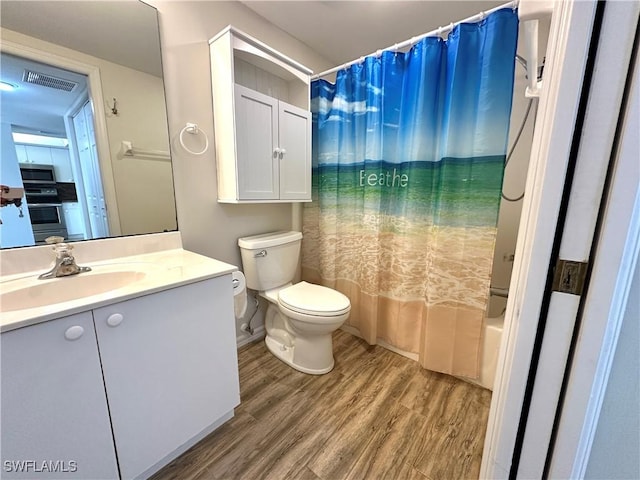 full bathroom featuring toilet, hardwood / wood-style floors, vanity, and shower / tub combo with curtain