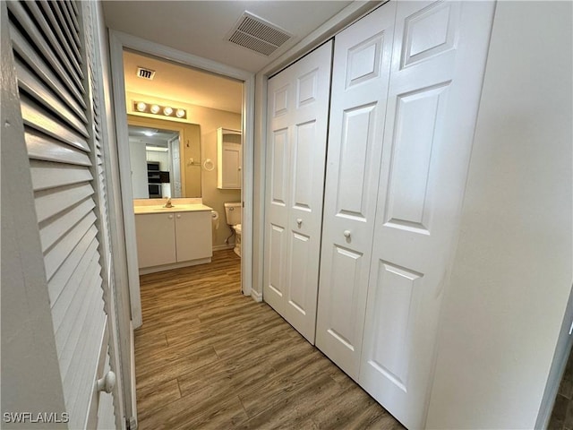 corridor featuring wood-type flooring and sink