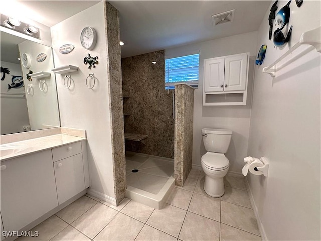 bathroom featuring tile patterned flooring, vanity, tiled shower, and toilet