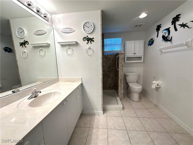 bathroom with tile patterned flooring, vanity, toilet, and a tile shower