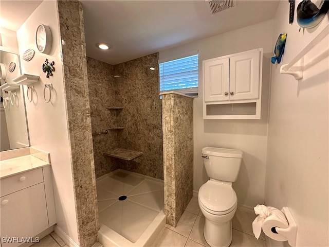 bathroom with tile patterned flooring, vanity, toilet, and tiled shower