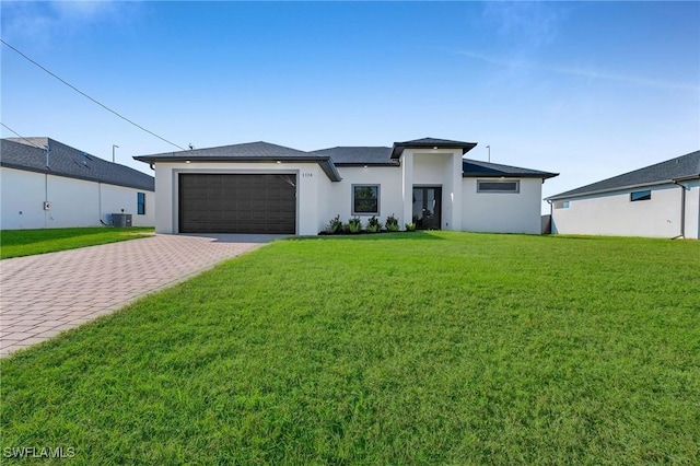 view of front of property with central air condition unit, a front yard, and a garage