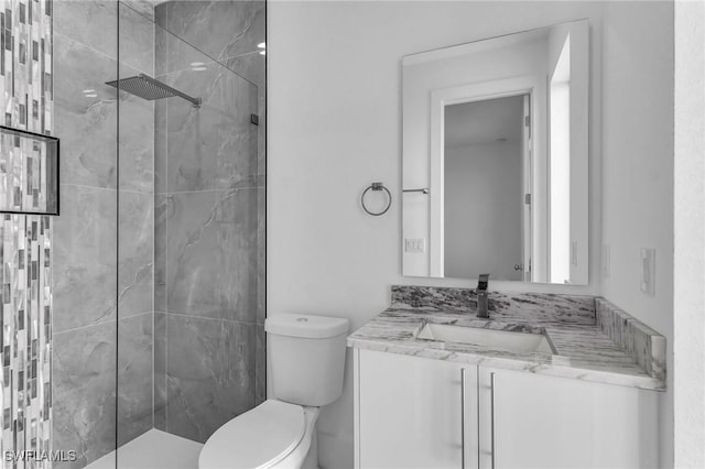 bathroom featuring tiled shower, vanity, and toilet