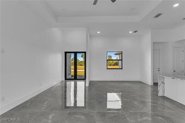 spare room featuring a tray ceiling and ceiling fan