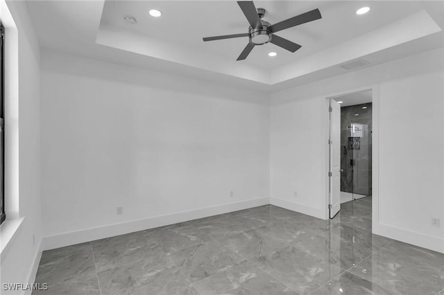 spare room with a tray ceiling and ceiling fan