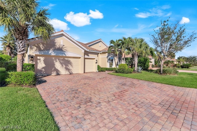 mediterranean / spanish-style house with a tiled roof, decorative driveway, an attached garage, a front lawn, and stucco siding