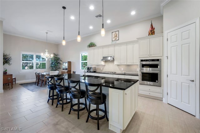 kitchen featuring visible vents, stainless steel double oven, under cabinet range hood, stovetop, and backsplash
