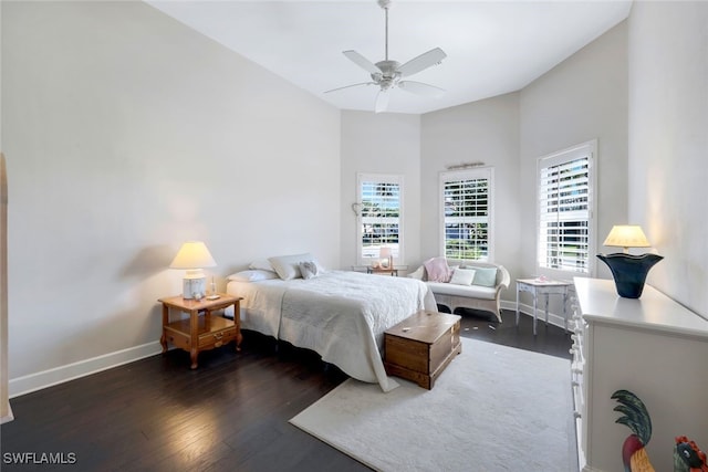bedroom with baseboards, dark wood-style flooring, a high ceiling, and a ceiling fan