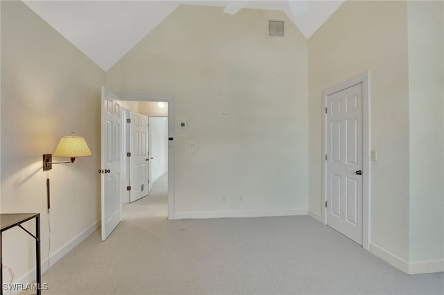 empty room featuring light colored carpet and high vaulted ceiling