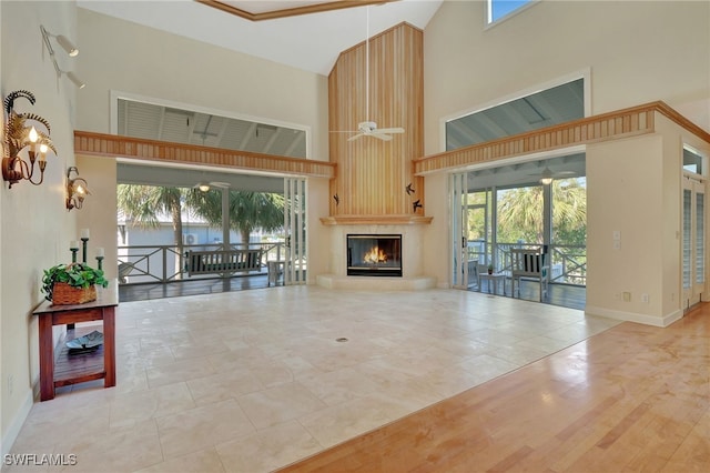 living room with ceiling fan, a large fireplace, wood-type flooring, and a towering ceiling