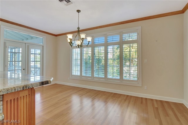 unfurnished dining area featuring ornamental molding, light hardwood / wood-style floors, an inviting chandelier, and a healthy amount of sunlight