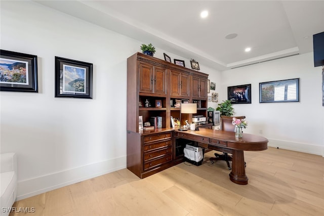 office space featuring light hardwood / wood-style floors and a raised ceiling