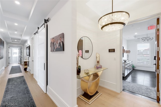 hallway featuring a barn door, a wealth of natural light, light hardwood / wood-style floors, and a notable chandelier