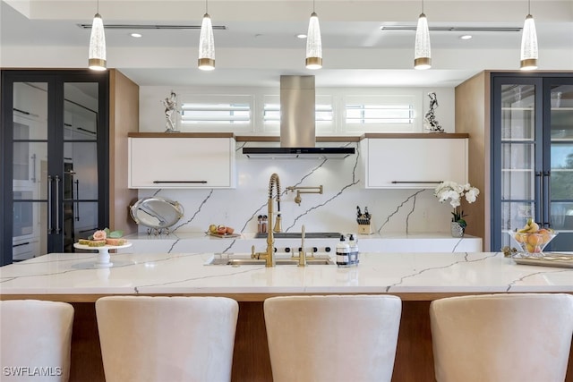 kitchen with pendant lighting, light stone counters, and island exhaust hood