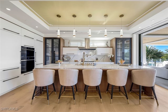 kitchen featuring a raised ceiling, white cabinetry, and pendant lighting