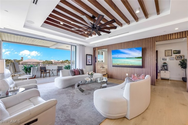 living room featuring a raised ceiling, ceiling fan, light hardwood / wood-style floors, and beam ceiling