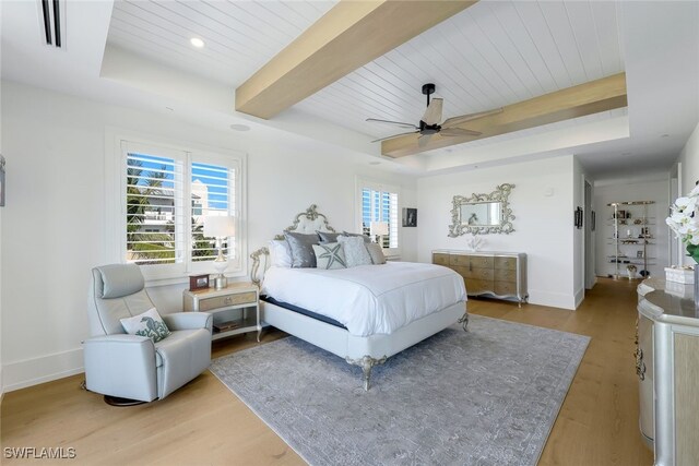 bedroom with beamed ceiling, ceiling fan, a raised ceiling, and light hardwood / wood-style flooring