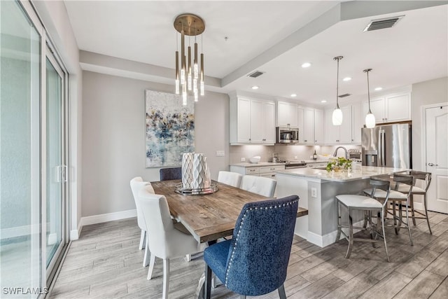 dining space with light hardwood / wood-style flooring and sink