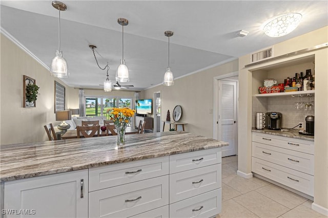 kitchen featuring white cabinets, light stone counters, crown molding, pendant lighting, and light tile patterned flooring