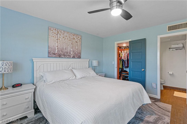 bedroom featuring hardwood / wood-style floors, a walk in closet, ceiling fan, connected bathroom, and a closet