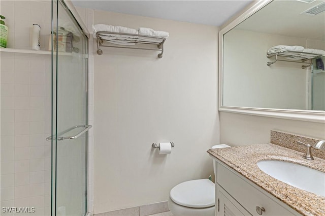 bathroom with tile patterned flooring, vanity, toilet, and walk in shower