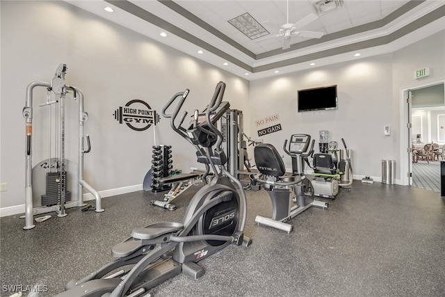 exercise room with ceiling fan, a raised ceiling, crown molding, and a high ceiling