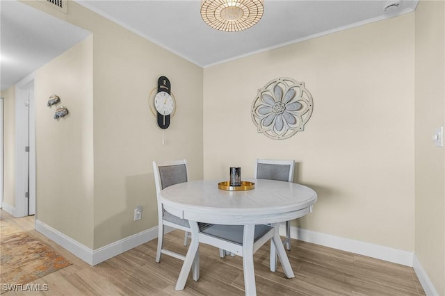 dining space featuring light hardwood / wood-style flooring and crown molding