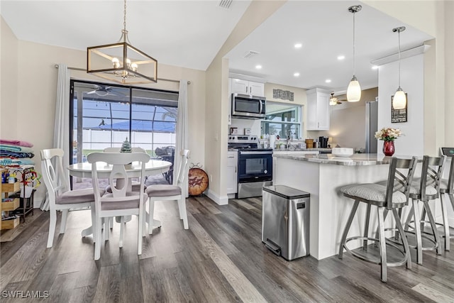 kitchen featuring white cabinets, pendant lighting, stainless steel appliances, and light stone countertops