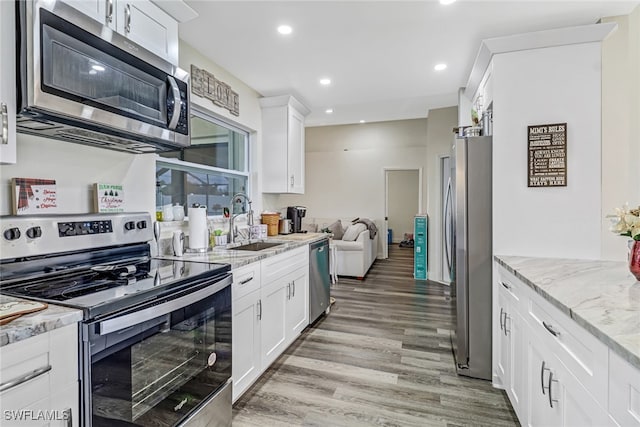 kitchen featuring appliances with stainless steel finishes, light hardwood / wood-style floors, white cabinetry, and sink