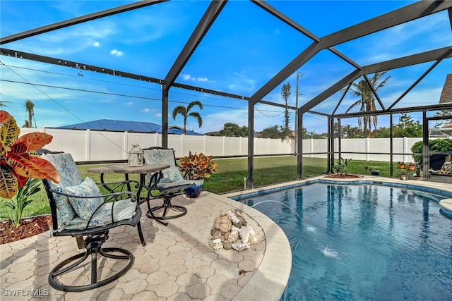 view of swimming pool featuring glass enclosure, a patio area, and a yard