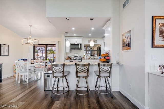 kitchen featuring kitchen peninsula, hanging light fixtures, white cabinets, and stainless steel appliances