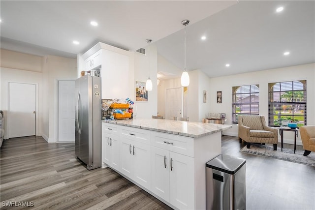 kitchen with pendant lighting, white cabinets, dark hardwood / wood-style floors, light stone counters, and stainless steel refrigerator