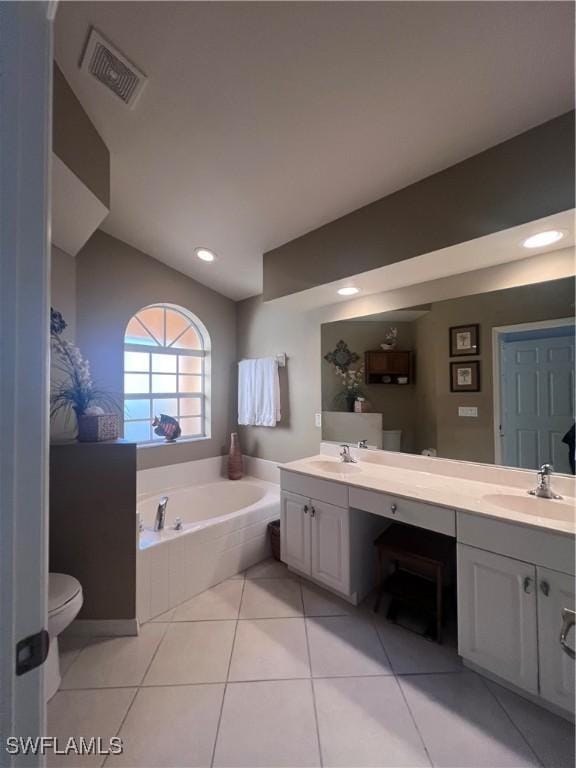 bathroom with toilet, vanity, a relaxing tiled tub, and tile patterned floors