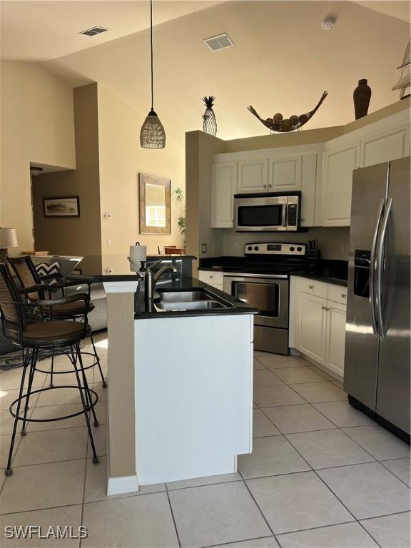 kitchen with pendant lighting, sink, light tile patterned floors, white cabinetry, and stainless steel appliances