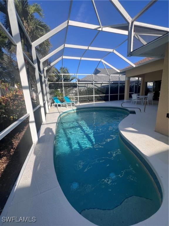 view of swimming pool with glass enclosure and a patio area