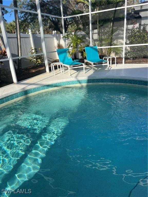 view of swimming pool with glass enclosure and a patio area