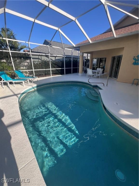 view of swimming pool with glass enclosure and a patio