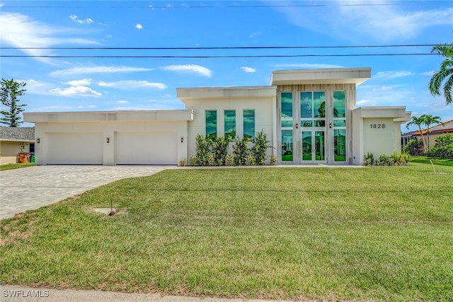 contemporary home featuring a garage, stucco siding, decorative driveway, and a front yard