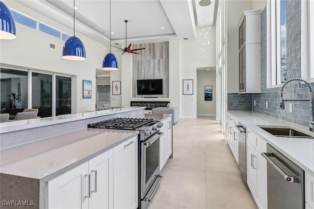 kitchen featuring stainless steel appliances, tasteful backsplash, hanging light fixtures, open floor plan, and a sink